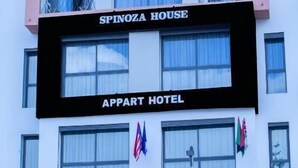 Un edificio de varios pisos con balcones y un letrero que dice "SPINOZA HOUSE" y "APPART HOTEL".