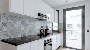 Una cocina moderna con armarios blancos, encimera negra y salpicadero con diseño.