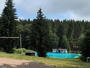 A pool area with a house and forest in the background. - Pure relaxation in the idyllic forest of Heimig (Suhl Ot. Schmiedefeld am Rennsteig)