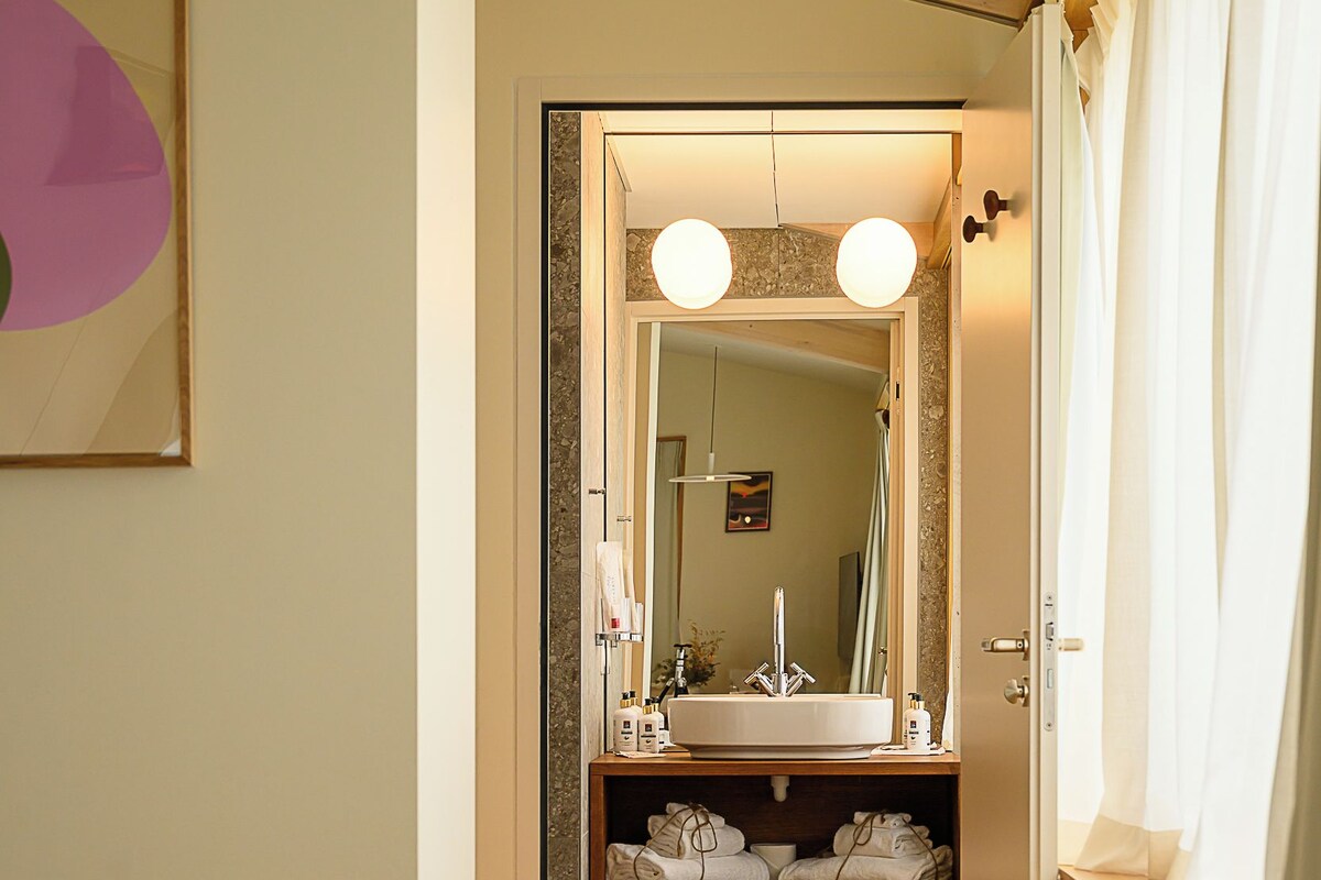 A hotel room with a bed, a bathroom with a sink, and a mirror.