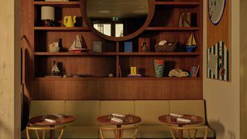 A cozy room with a wooden bookshelf, a round mirror, and a seating area with two round tables and chairs.