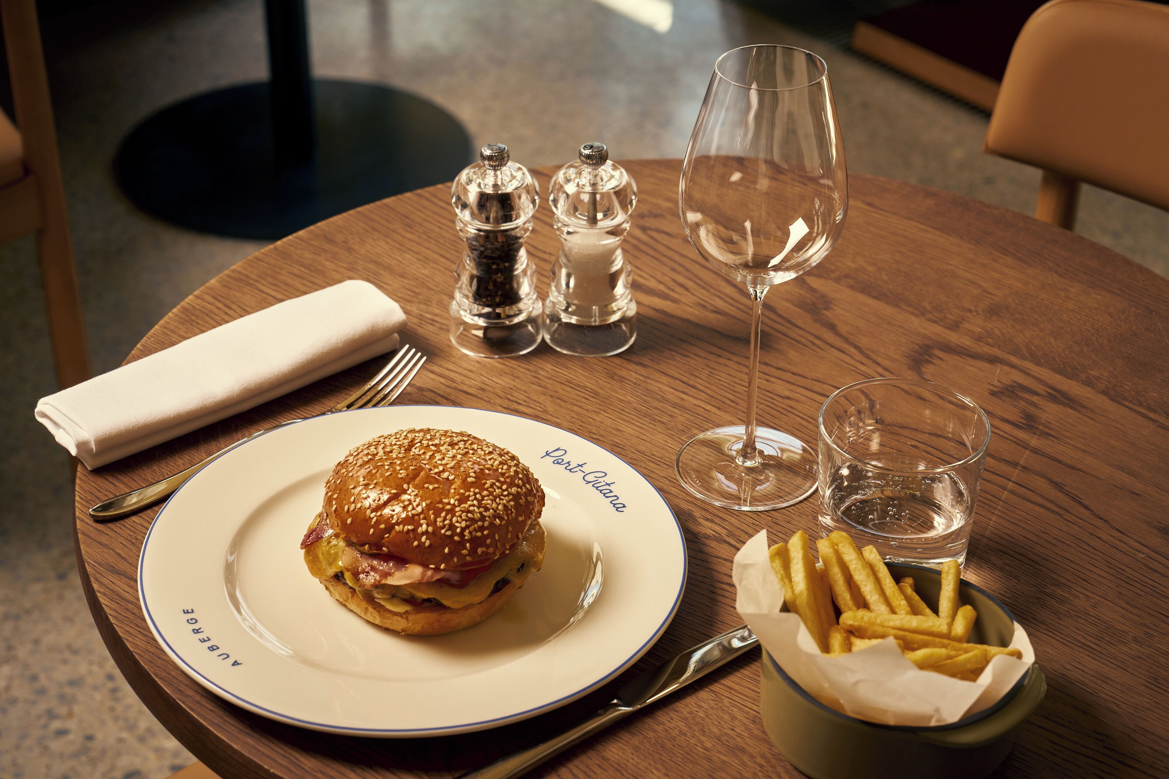 A wooden table with a plate of food, a glass of water, salt and pepper shakers, a napkin, and cutlery.