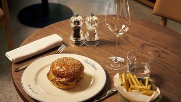 A wooden table with a plate of food, a glass of water, salt and pepper shakers, a napkin, and cutlery.