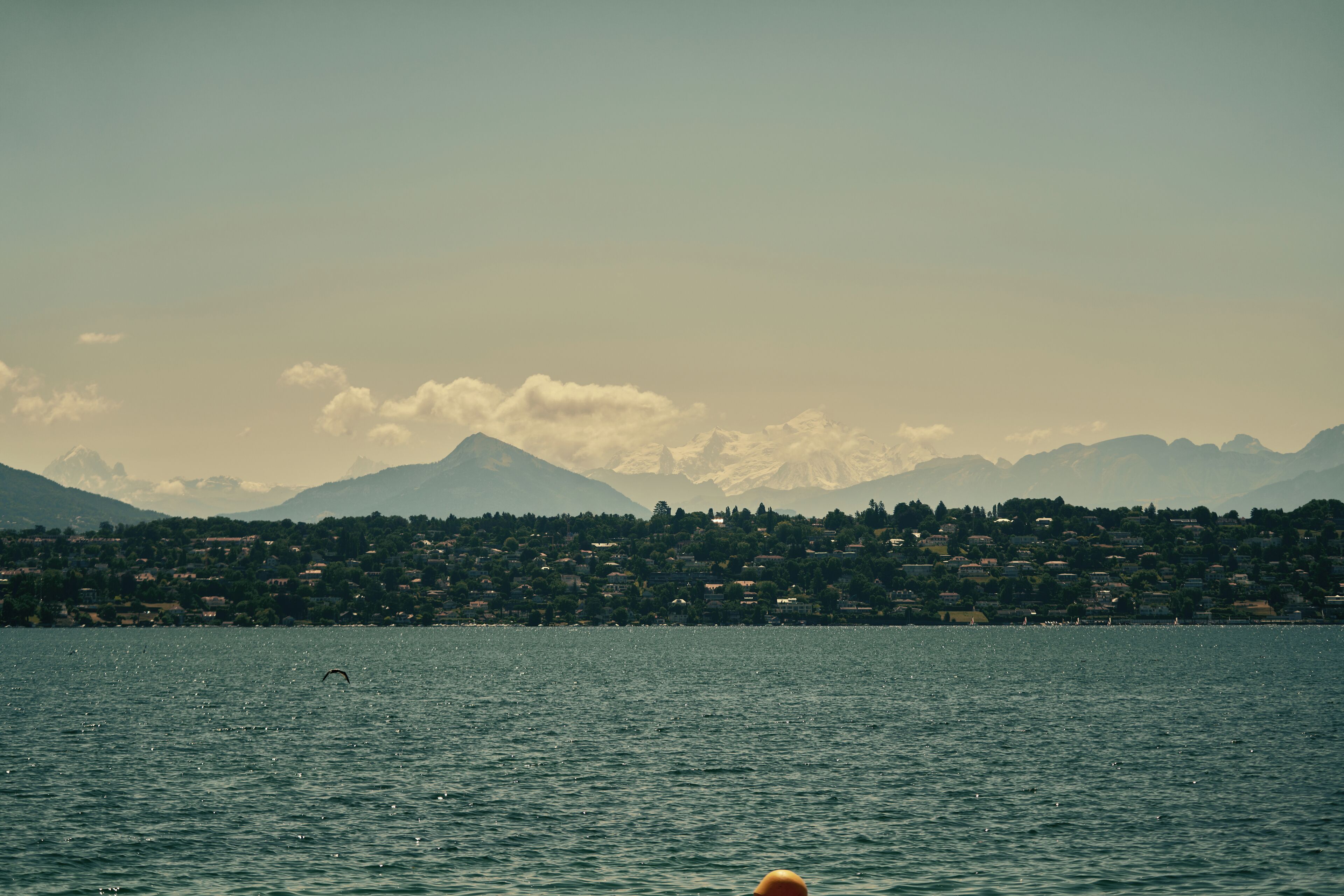 A lake with a distant mountain range and a town across the water.