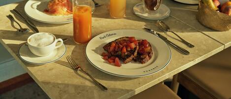 A breakfast table with plates of food, a coffee cup, and a fruit basket.