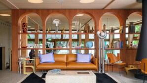 A modern living room with a leather sofa, a coffee table, and a bookshelf filled with books and decorative items. - Auberge Port Gitana (Bellevue)