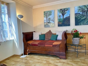 Un canapé en bois avec des coussins à motifs, un lampadaire et une plante en pot.