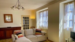 Uma sala de estar com sofá, televisão, aparador de madeira e uma porta.