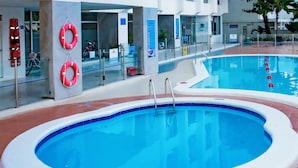 Une piscine intérieure à l’eau claire, avec une bouée de sauvetage et un vélo en arrière-plan.