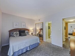 A bedroom with a bed, a nightstand, and a mirror. There are two framed pictures on the wall.