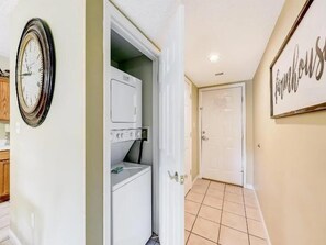 A hallway with a clock, a laundry area with a washer and dryer, and a door leading to another room. - 3BR Condo with Pools & Lazy River in Pigeon Forge (Pigeon Forge)