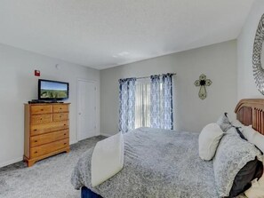 A bedroom with a bed, a dresser, a television, and a window with curtains. - 3BR Condo with Pools & Lazy River in Pigeon Forge (Pigeon Forge)