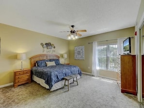A bedroom with a bed, bedside tables, a bench, a ceiling fan, a window with curtains, and a TV. - 3BR Condo with Pools & Lazy River in Pigeon Forge (Pigeon Forge)
