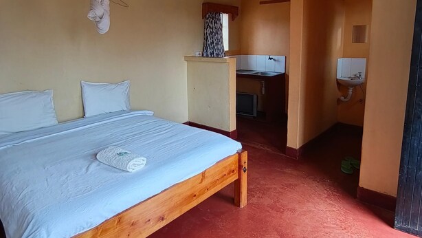 A room with a wooden bed, a small desk, a sink, and a ceiling fan. - Charming bed & breakfast with WiFi in Nyeri (Nyeri)