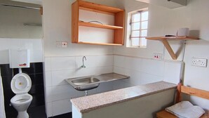 A compact kitchen with a sink, wooden shelves, and a small wooden stool. - Charming bed & breakfast with WiFi in Nyeri (Nyeri)