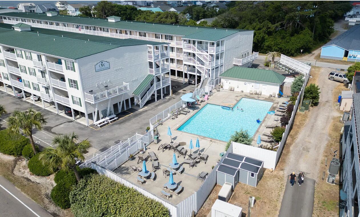 Ein mehrstöckiges Hotel mit Schwimmbad, Außenbereich und Parkplatz.
