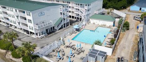 Ein mehrstöckiges Hotel mit Schwimmbad, Außenbereich und Parkplatz.