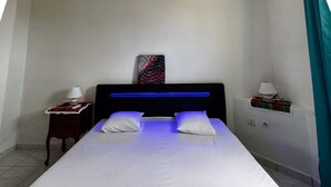A neatly made bed with white linens and two pillows, a bedside table with a lamp, a small decorative item, and a painting on the wall. - Mont loué - Maison 6 personnes (Trois Rivieres)