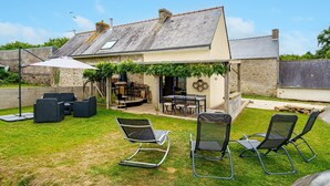 A house with a patio area featuring outdoor furniture, a dining table, and a barbecue setup.