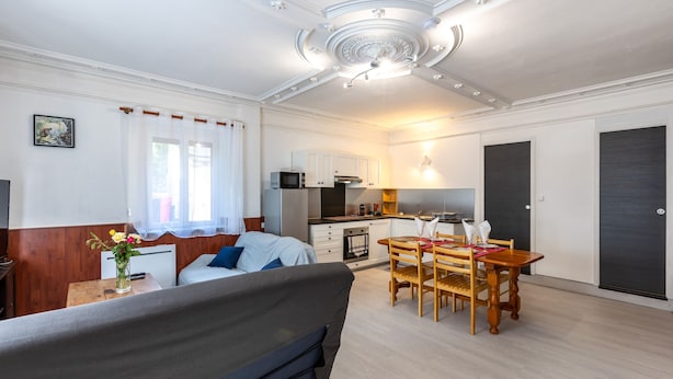 Una habitación compacta y bien iluminada con kitchenette, comedor y cama.