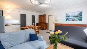 Una sala moderna con un sofá, una mesa de comedor y una zona de cocina al fondo.