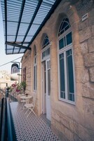 Un edificio de piedra con ventanas arqueadas y un espacio exterior cubierto con una mesa y sillas.