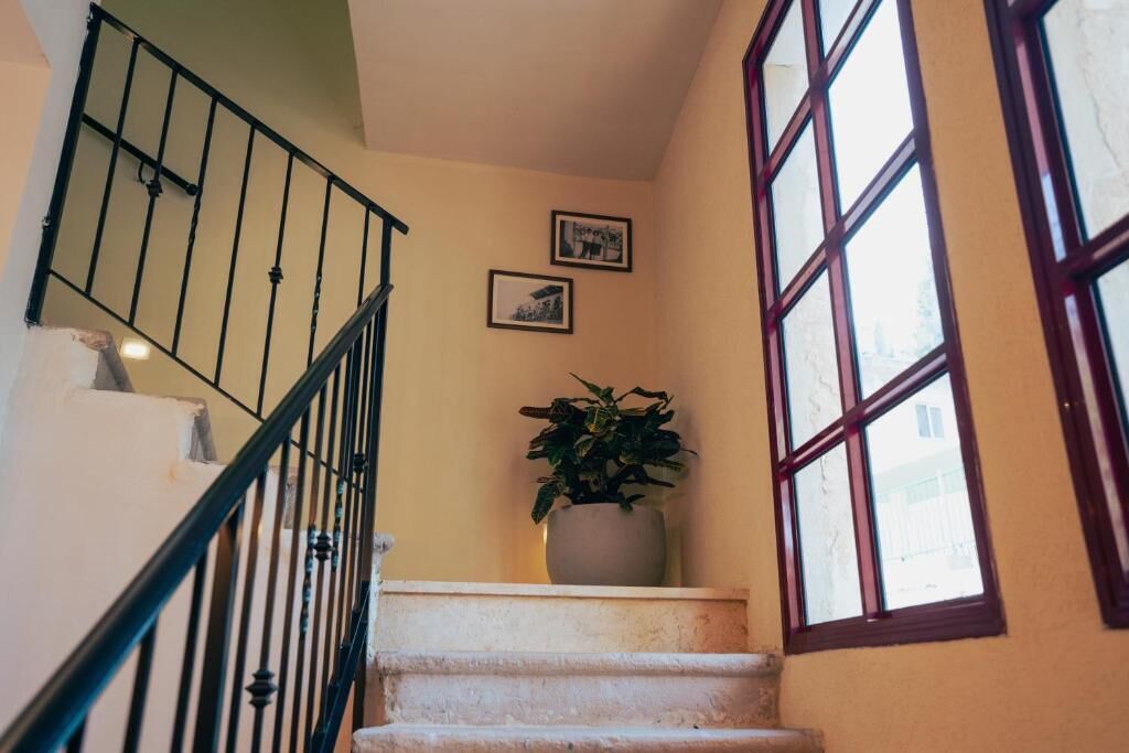 Un escalier avec une rampe noire, une plante en pot sur le palier et deux tableaux encadrés au mur.