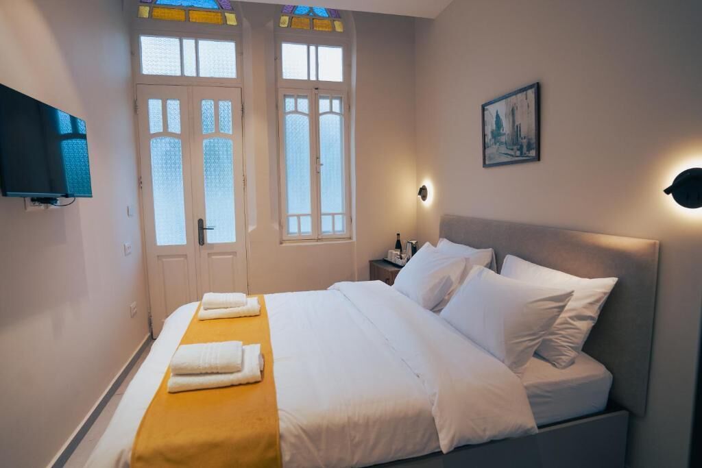 Une chambre d’hôtel avec un lit, une télévision, une table de chevet et un tableau au mur.
