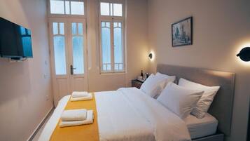 Une chambre d’hôtel avec un lit, une télévision, une table de chevet et un tableau au mur.