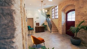 A spacious interior with a staircase, a red door, and a potted plant. - Roots Boutique Hotel (Nazareth)