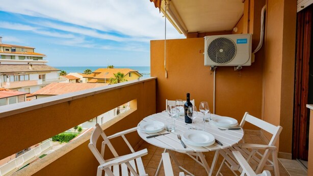 Ein Balkon mit Esstisch, Klimaanlage und Meerblick.