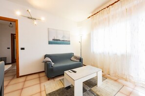 A living room with a sofa, a coffee table, a painting, and a lamp.