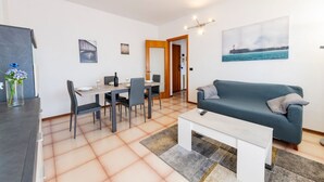 Ein modernes Wohnzimmer mit einer Couch, einem Esstisch, Stühlen und einem Couchtisch.