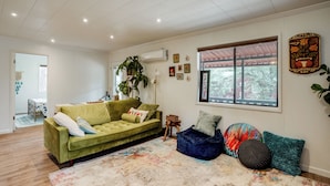 Una sala de estar con un sofá verde, un sillón orejero azul y una alfombra colorida.