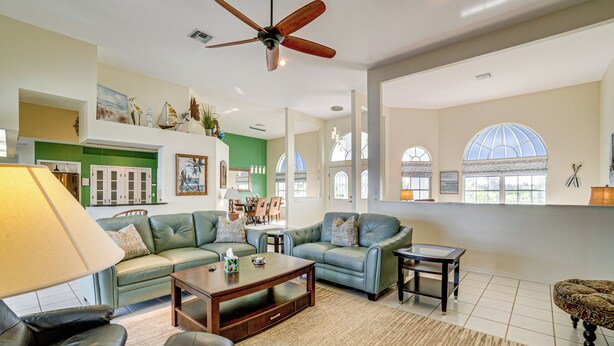 A spacious living room with a ceiling fan, green and white walls, a large window, and a dining area in the background. - Poolside Bliss & Lake Fun: Florida Getaway! (Fort Ogden)