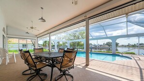 A covered patio with a pool view, outdoor dining set, and ceiling fans. - Poolside Bliss & Lake Fun: Florida Getaway! (Fort Ogden)
