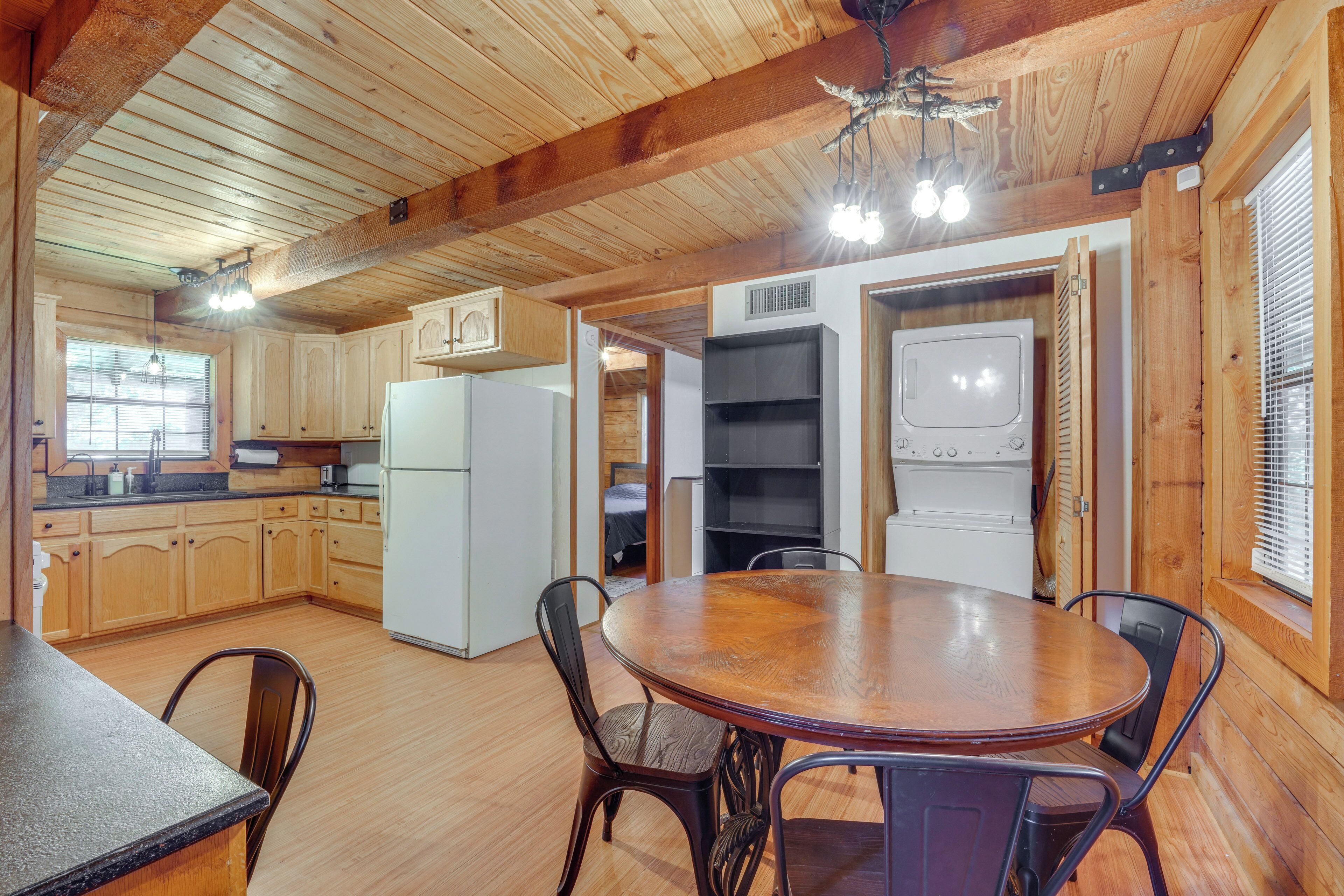 Interior de una cabaña de madera con cocina, comedor y ventilador de techo.