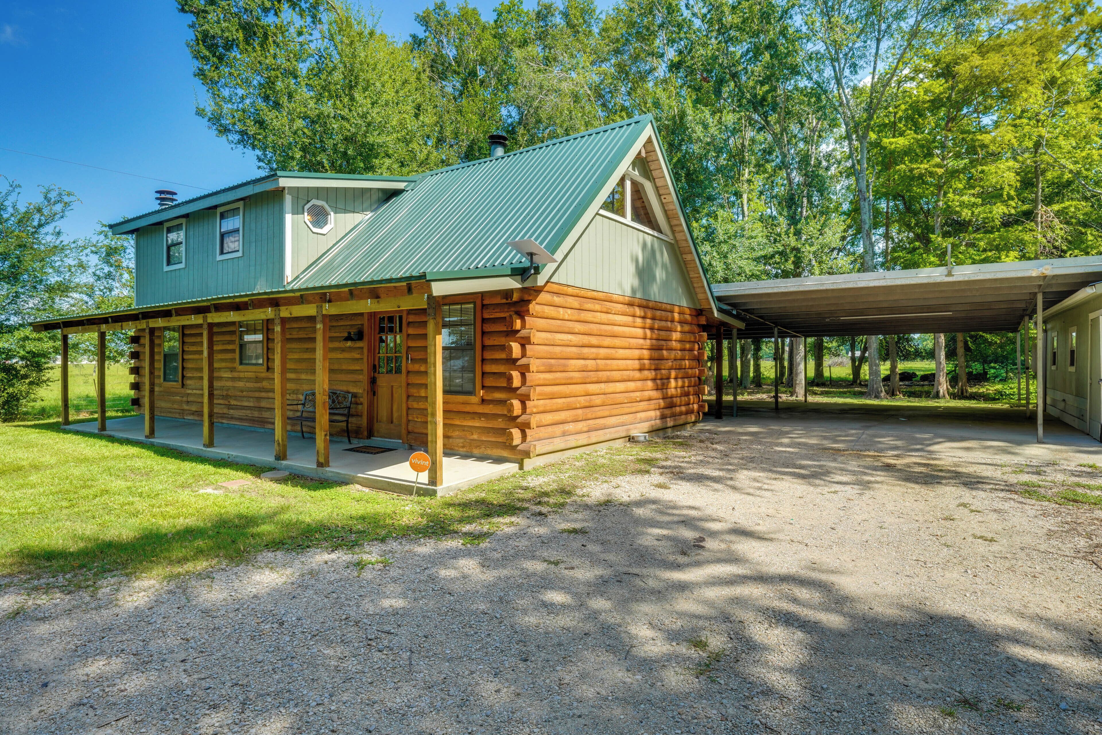 Une cabane en rondins avec un toit végétalisé et une véranda couverte.