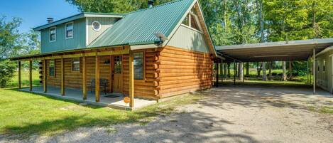 Une cabane en rondins avec un toit végétalisé et une véranda couverte.