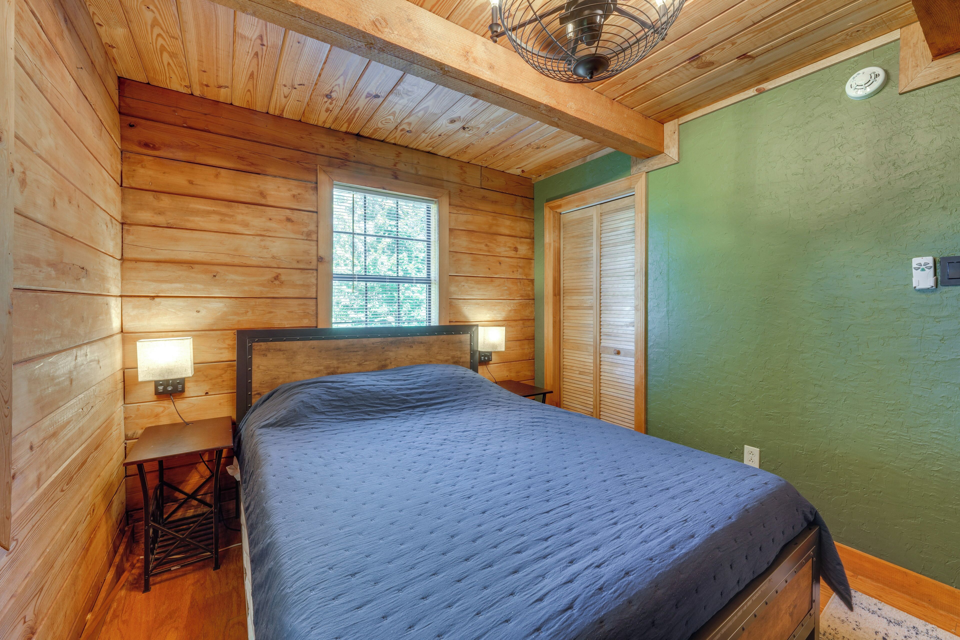 A wooden cabin bedroom with a bed, a small table, and a window.