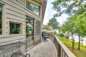 A deck with outdoor furniture, a metal cart, and a glass door leading to a covered area.