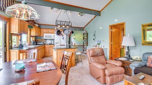 A spacious kitchen with wooden cabinets, a dining area with a wooden table, and a living room with a leather chair and a sofa. - Boat Dock Access: Clarks Hill Lake Hideaway! (Elberton)