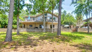 A two-story house with a balcony, surrounded by trees and a stone wall. - Boat Dock Access: Clarks Hill Lake Hideaway! (Elberton)