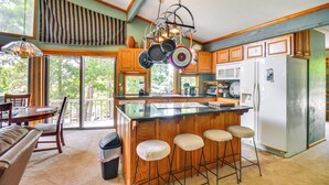 A kitchen with a large island, wooden cabinets, and a hanging pot rack. - Boat Dock Access: Clarks Hill Lake Hideaway! (Elberton)