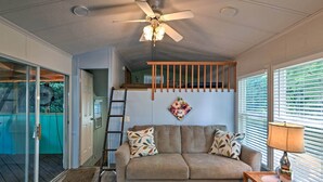 A cozy living room with a beige sofa, a wooden coffee table, and a ceiling fan. - Resort Cabin 1 Mi to Middle Bass Island State Park (Put-in-Bay)