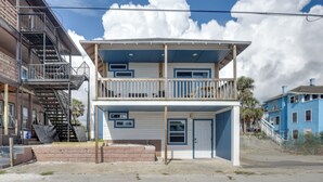 A two-story building with a balcony on the upper floor, a door on the lower floor, and a staircase on the left side. - Walk to Daytona Beach & Boardwalk: Apt w/ Balcony (Daytona Beach)
