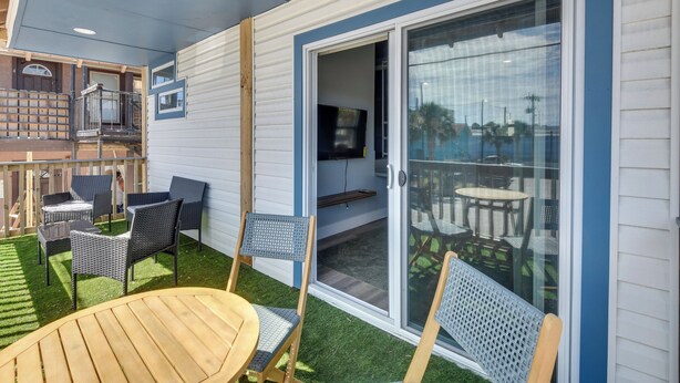 A covered outdoor area with a patio, seating, and a sliding glass door leading to an interior space. - Walk to Daytona Beach & Boardwalk: Apt w/ Balcony (Daytona Beach)
