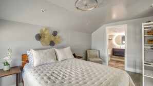 A bedroom with a large bed, a nightstand, a chair, a wardrobe, and a ceiling fan. - Walk to Daytona Beach & Boardwalk: Apt w/ Balcony (Daytona Beach)