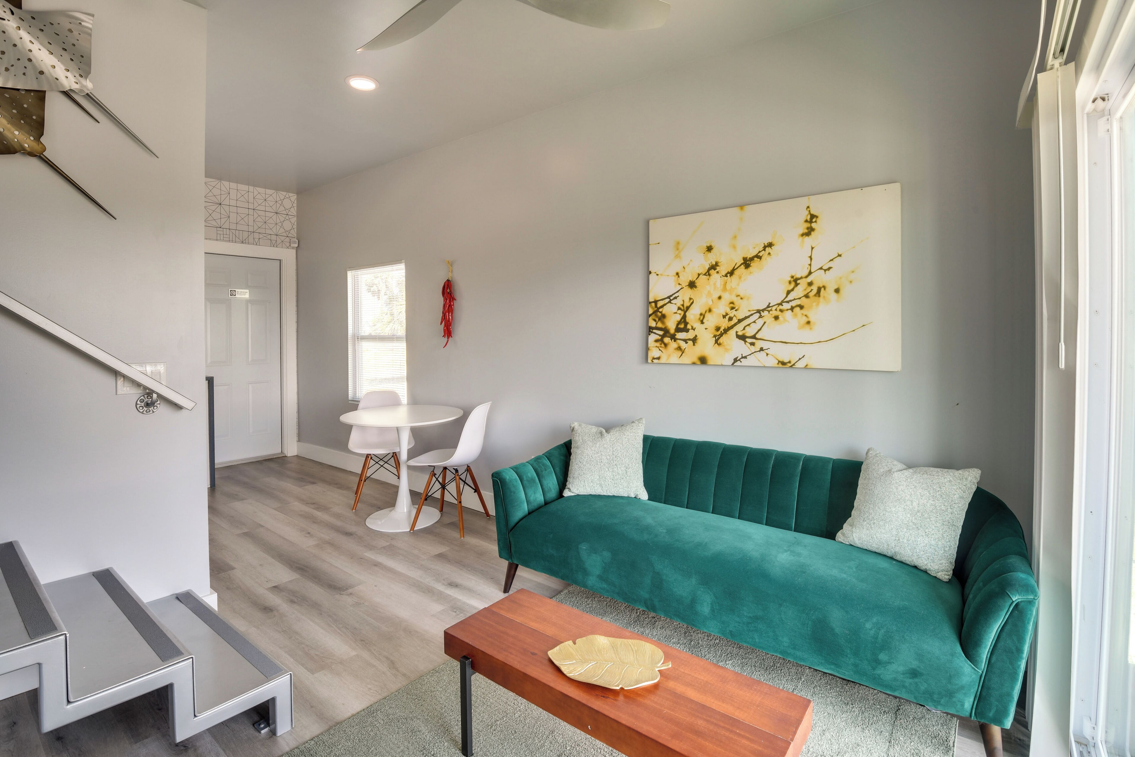 Un salon moderne avec un canapé de couleur turquoise, une table basse en bois et un coin repas comprenant une table et des chaises blanches.