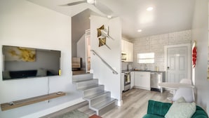 A modern living room with a green sofa, a wooden coffee table, and a flat-screen TV mounted on the wall. - Walk to Daytona Beach & Boardwalk: Apt w/ Balcony (Daytona Beach)